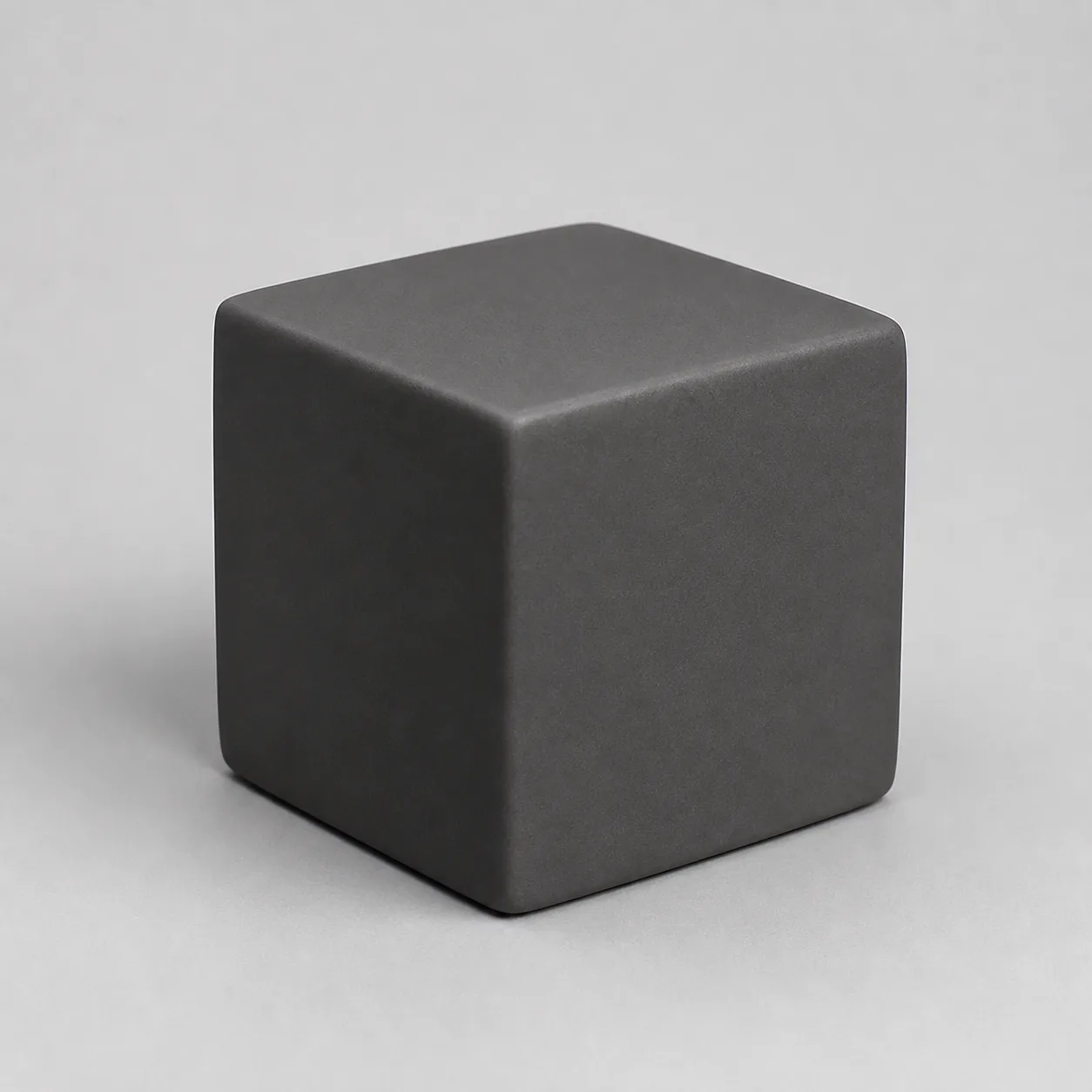 Minh họa cho “Độ phản chiếu”: a matte charcoal ceramic cube with soft diffuse highlights and no mirror-like reflections.